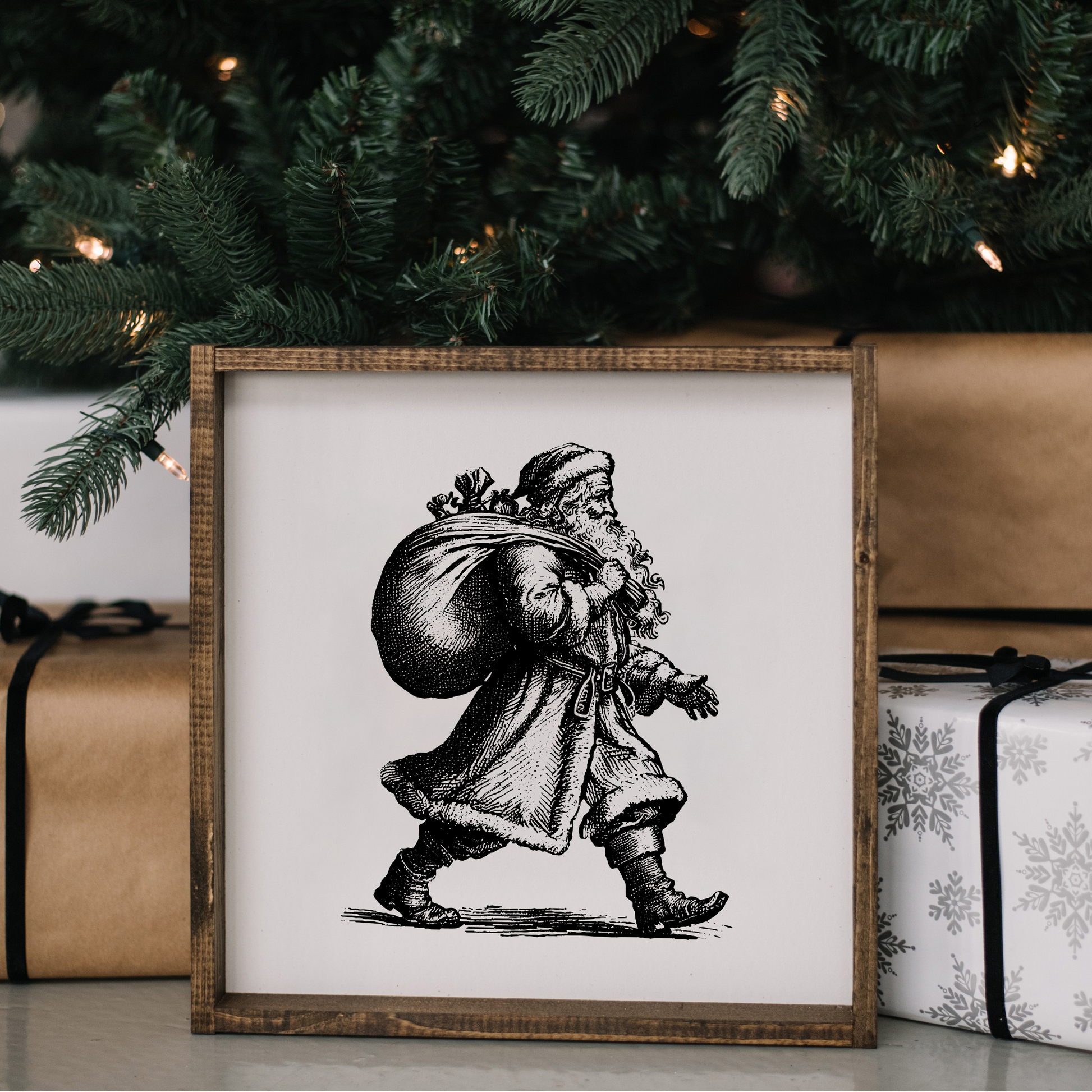 Framed black and white illustration of a Santa Claus figure in front of Christmas presents and tree.